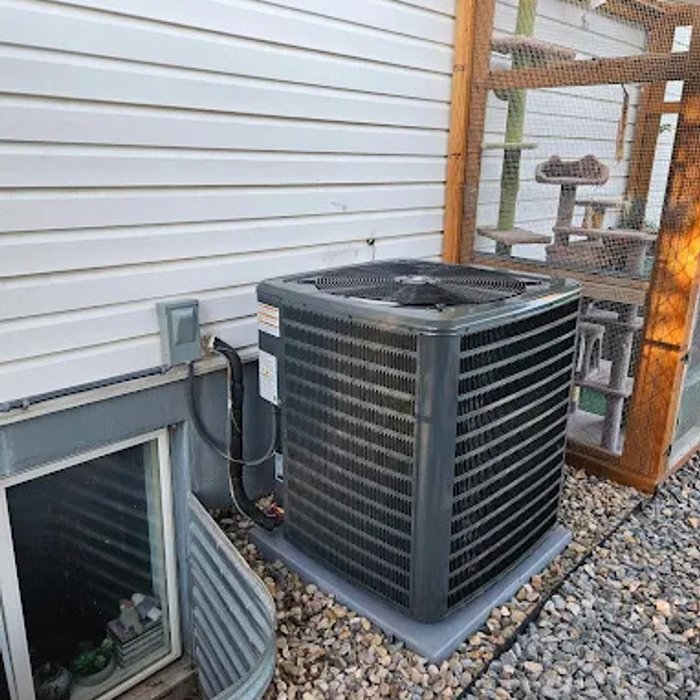 Heat pump condenser installed beside a home's window well