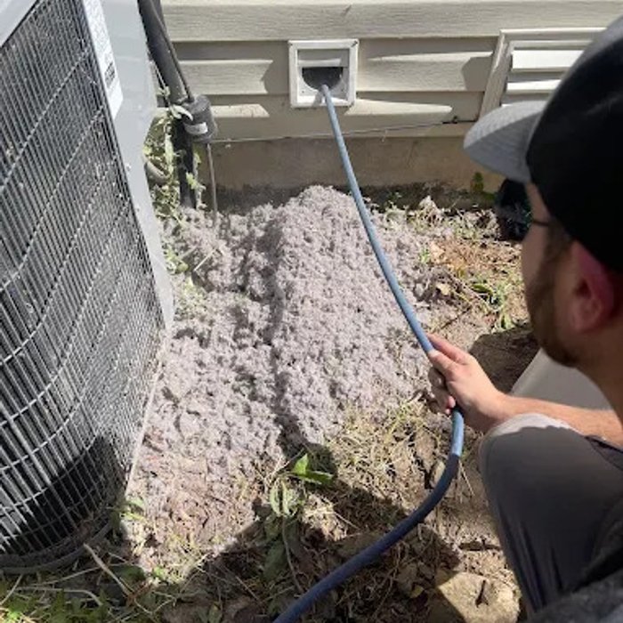 Technician clearing dust and debris from an outdoor vent line
