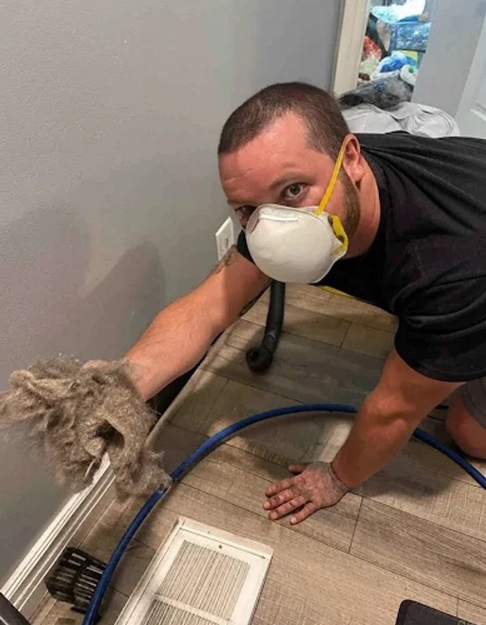 Technician cleaning a floor vent register by hand